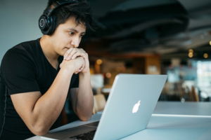 man wearing headphones while sitting on chair in front of MacBook