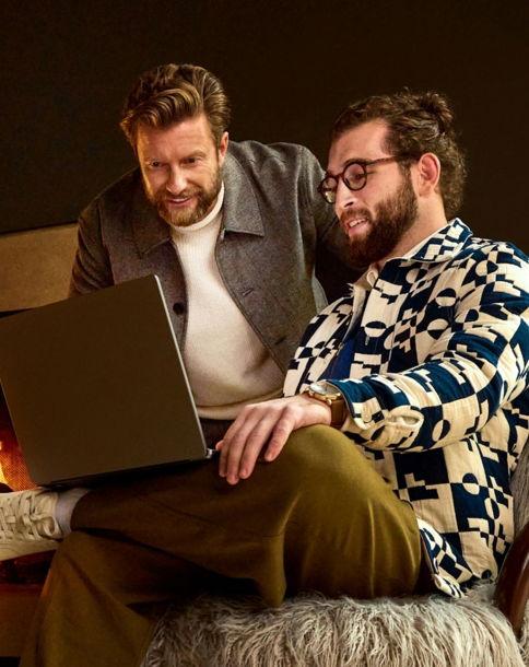 Two men looking at a laptop near a fireplace
